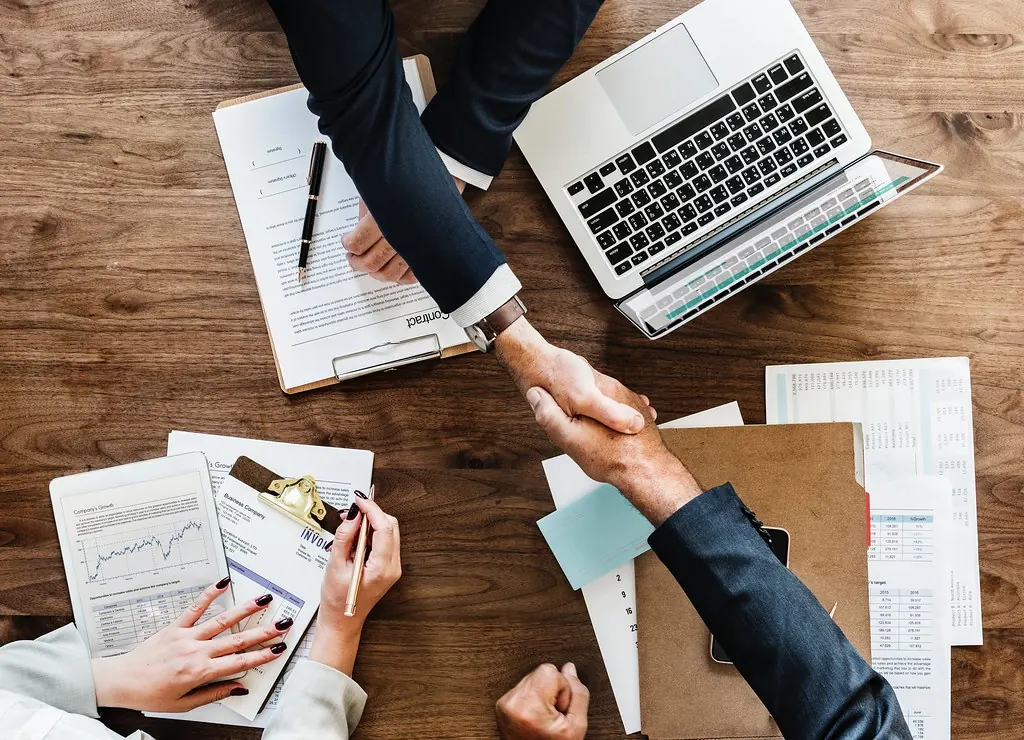 Persona estrechando la mano tras firmar un documento